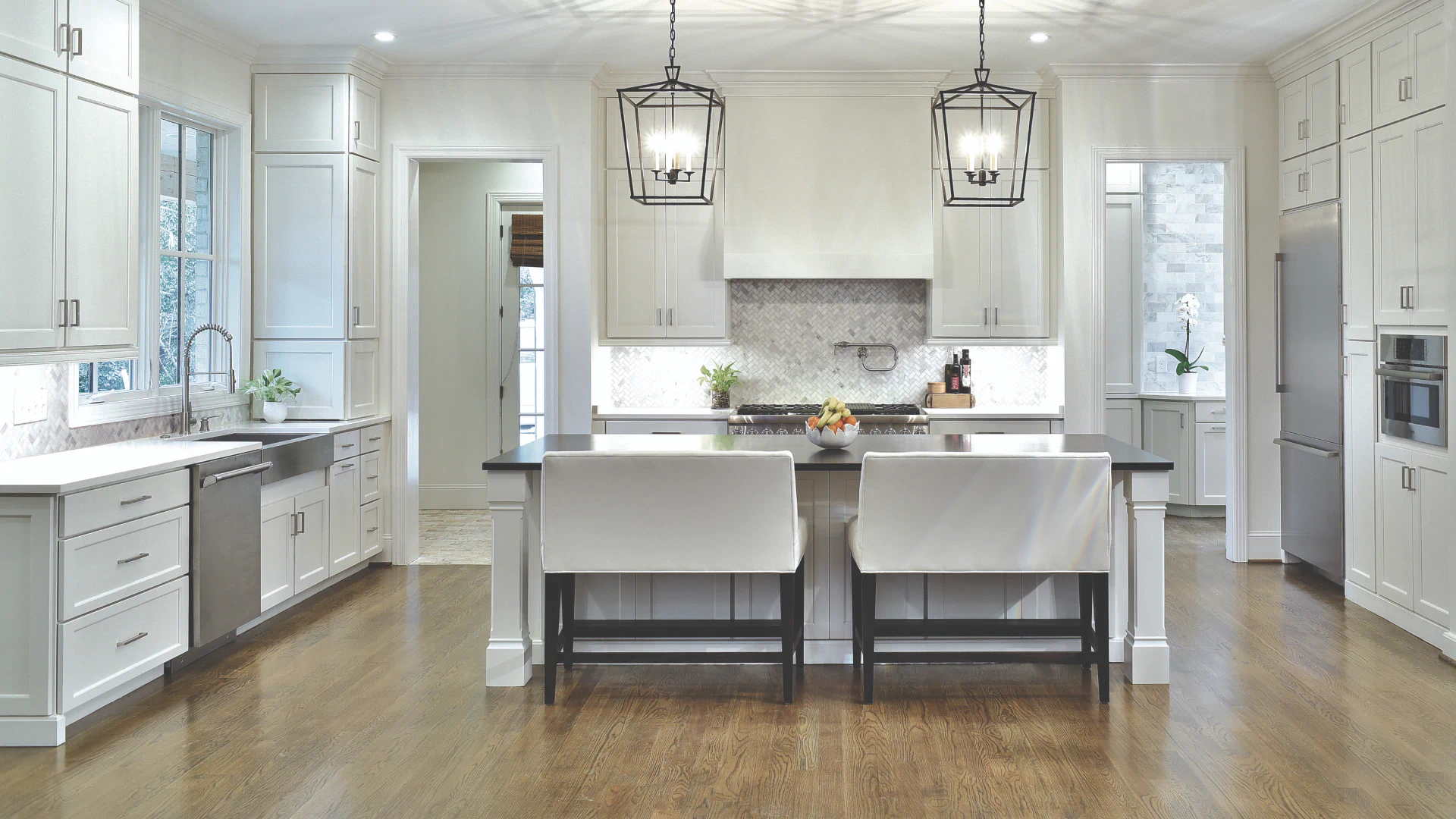 luxurious kitchen with white cabinets and hanging lights above island countertop